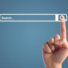 The index finger of a person clicking on a search button next to a search bar. Image by 19 Studio via Shutterstock.