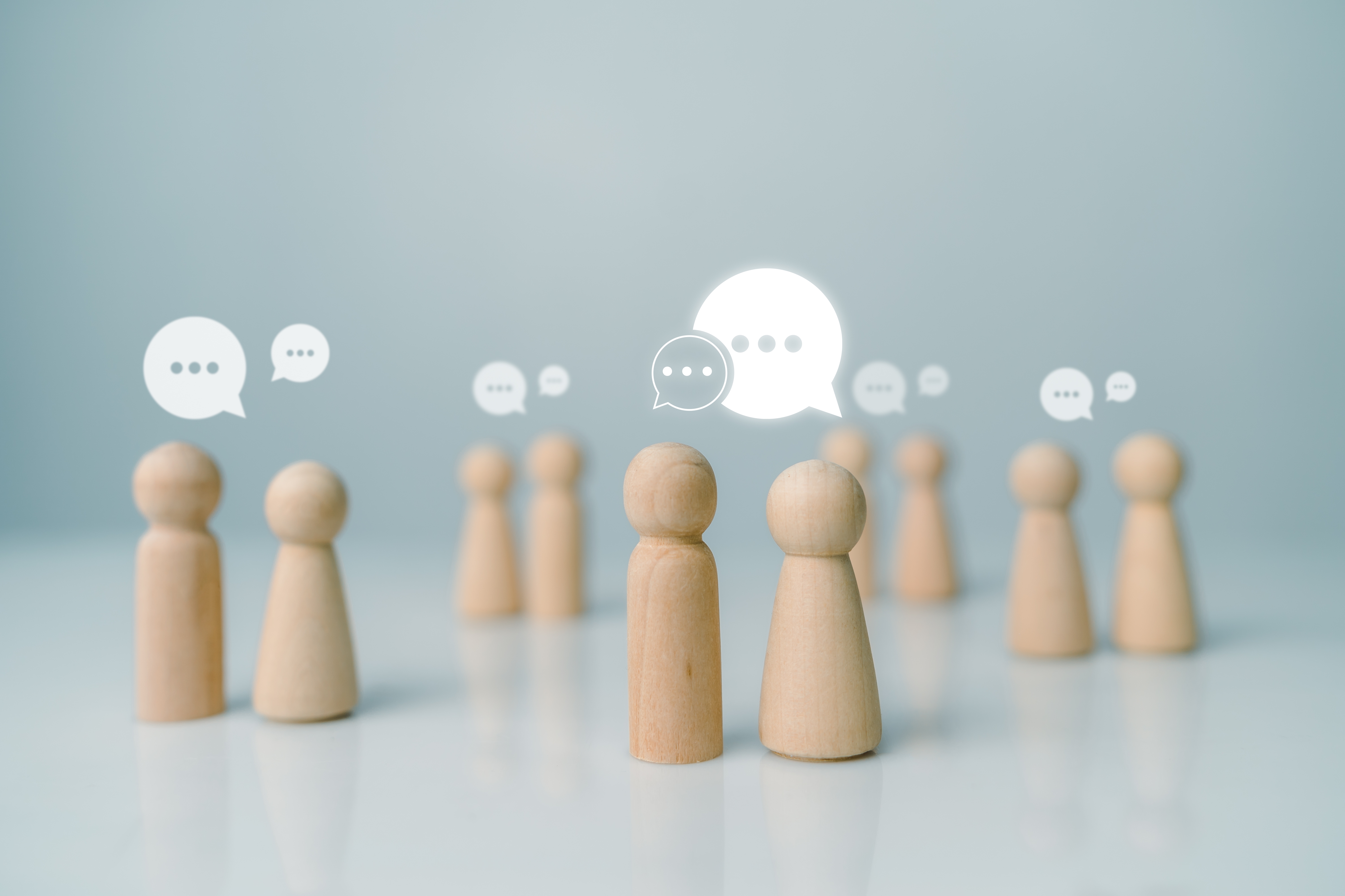 Little wooden figurines talking to each other, representing networking. Image by THEBILLJR via Shutterstock.