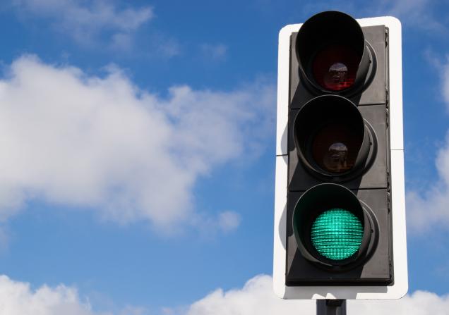 A green traffic light against a blue sky with a few fluffy white clouds. Image by Eddie J. Rodriquez via Shutterstock.