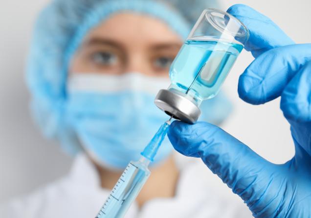 Doctor filling syringe with medication, closeup. Vaccination and immunization. Image by New Africa via Shutterstock