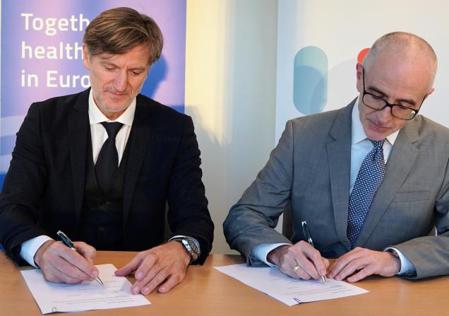 Jean-Marc Bourez, CEO of EIT Health, and Hugh Laverty, Executive Director ad interim of IHI JU, sign the Memorandum of Understanding. They are sitting next to each other at a table. Both are wearing suits and a tie. Image by IHI Programme Office.