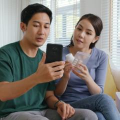 A young couple consult the apps to find out information about their medication. Image by Chay_Tee via Shutterstock.
